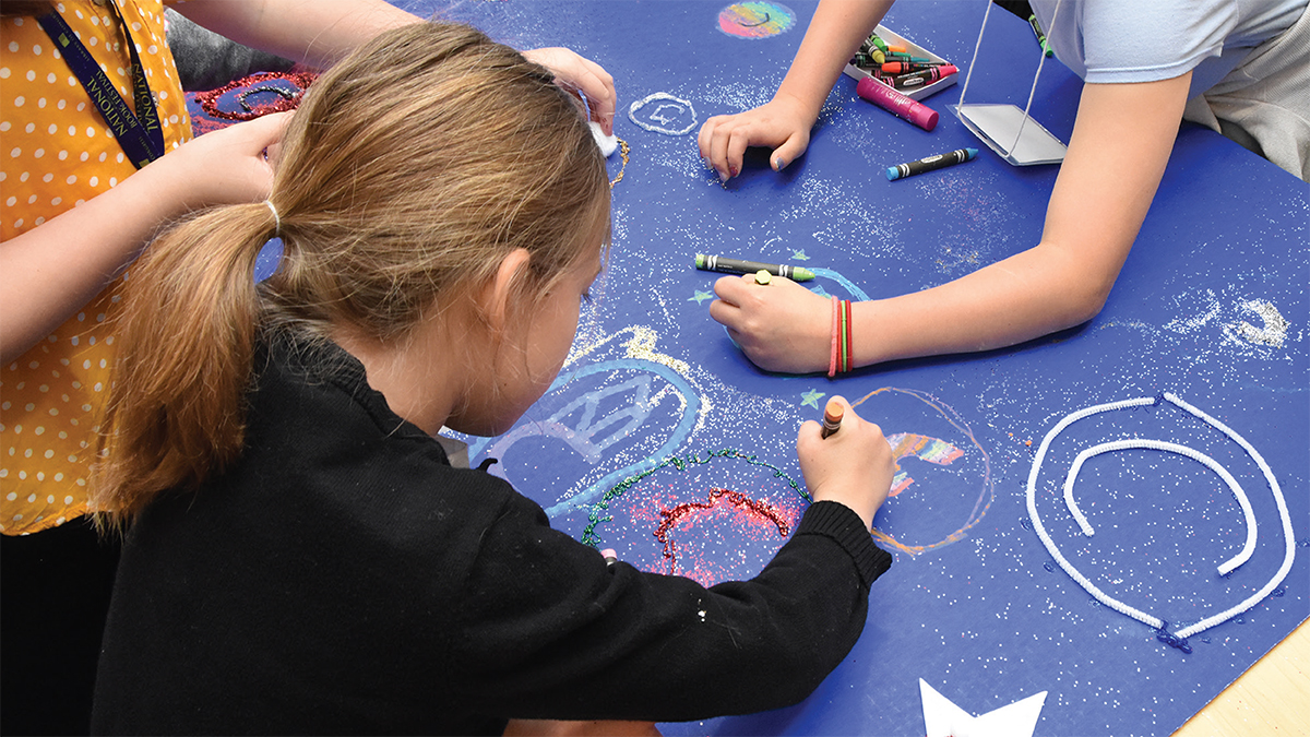 Children draw copyright images on a blue poster